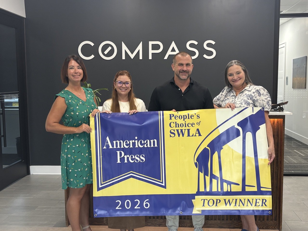 The Carroll & Carlisle Group team holding the 2026 American Press People’s Choice of SWLA Top Winner banner at the Compass office in Lake Charles